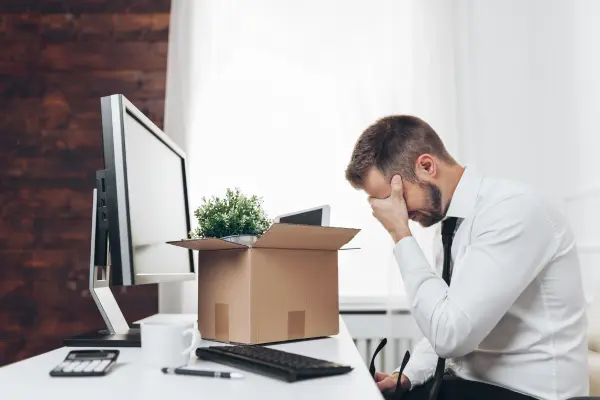 Employee visibly upset at this office desk with a box of personal items